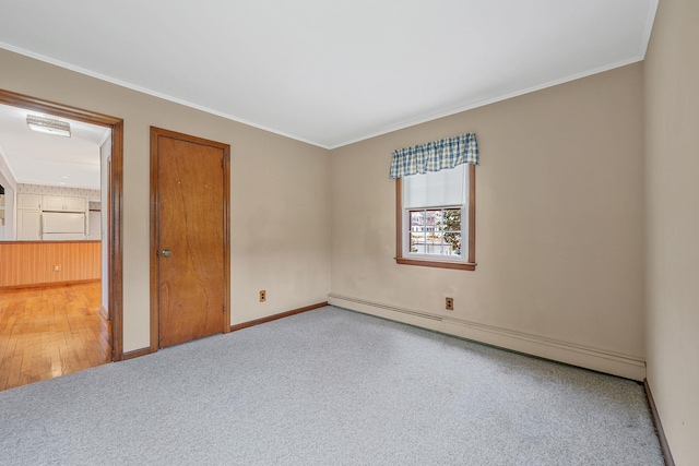 carpeted empty room featuring crown molding, baseboards, and baseboard heating