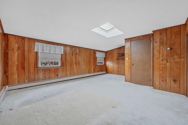 additional living space featuring a baseboard heating unit, a skylight, wooden walls, and carpet