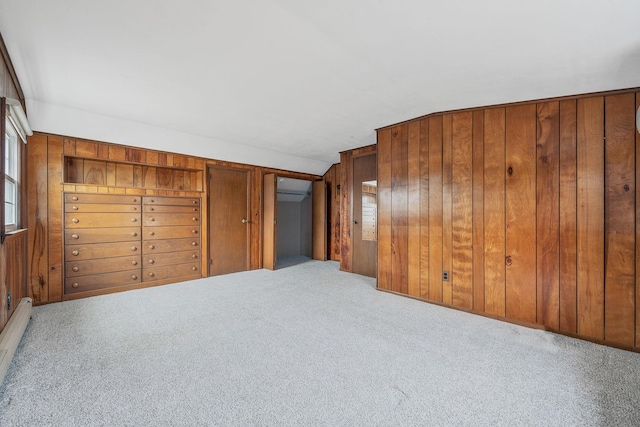 interior space featuring lofted ceiling, wooden walls, carpet flooring, and a baseboard radiator