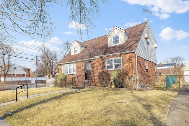 new england style home with fence, brick siding, a front yard, and a gate