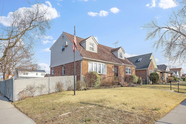 view of front facade featuring brick siding, a front lawn, and fence