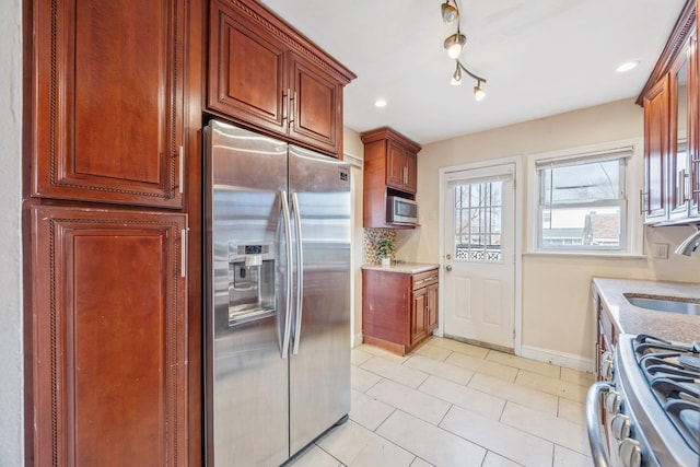 kitchen featuring baseboards, light tile patterned floors, recessed lighting, stainless steel appliances, and a sink