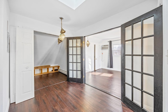 unfurnished room with a wall mounted air conditioner, a baseboard heating unit, dark wood-style flooring, and french doors