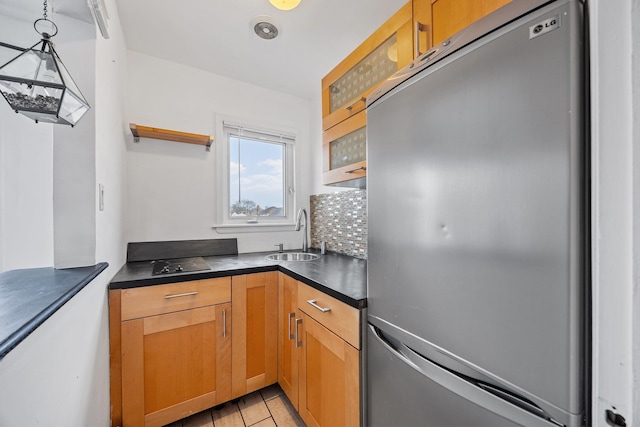 kitchen with open shelves, freestanding refrigerator, a sink, dark countertops, and tasteful backsplash