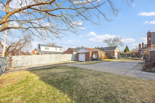 view of front of property featuring a front yard, an outbuilding, fence, concrete driveway, and a garage