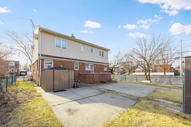 back of house featuring brick siding, driveway, a patio, and fence