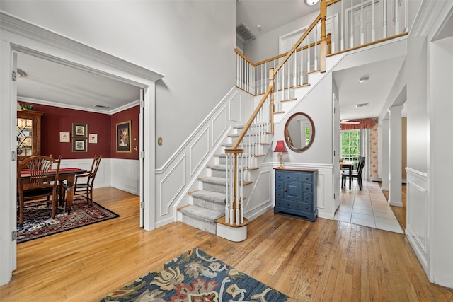 33 Sutherland Dr, Highland Mills, NY 10930 - staircase featuring wood-type flooring, wainscoting, a towering ceiling, a decorative wall, and ornate columns