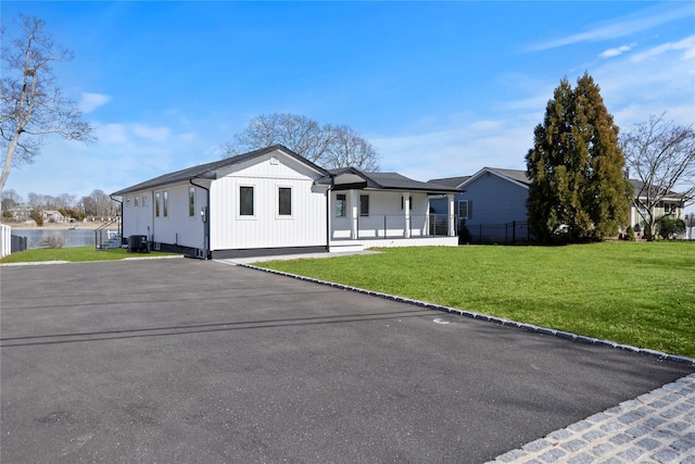 modern farmhouse featuring cooling unit, board and batten siding, and a front yard