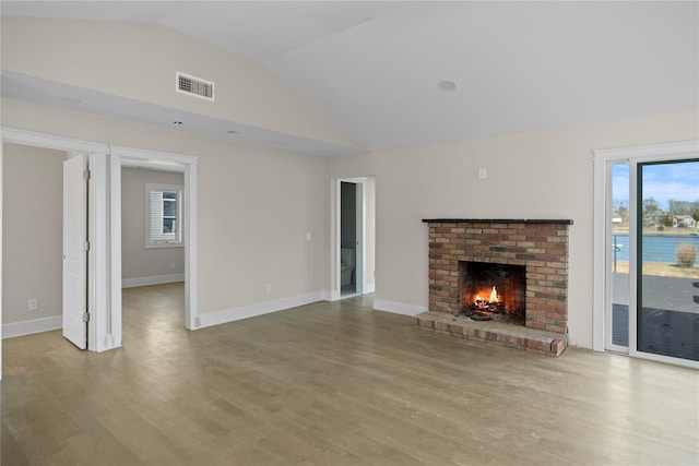 unfurnished living room featuring high vaulted ceiling, baseboards, visible vents, a fireplace, and wood finished floors
