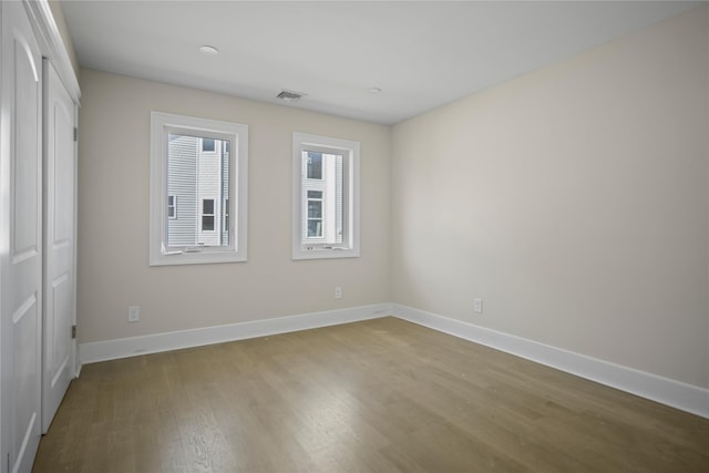 unfurnished bedroom featuring baseboards, visible vents, and wood finished floors