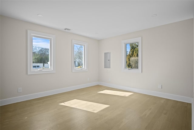 spare room featuring baseboards, visible vents, electric panel, and wood finished floors