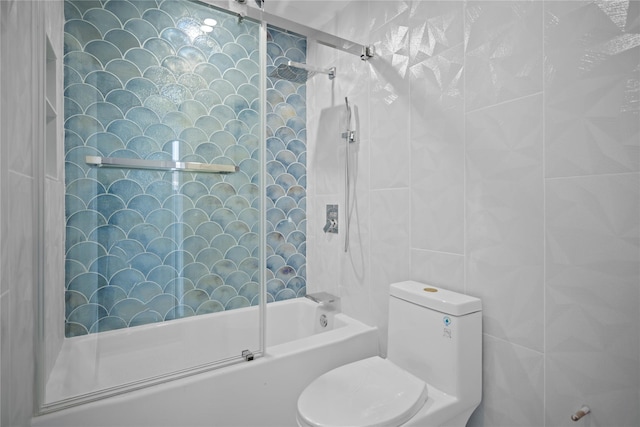 bathroom with shower / bath combination with glass door, toilet, and tile walls