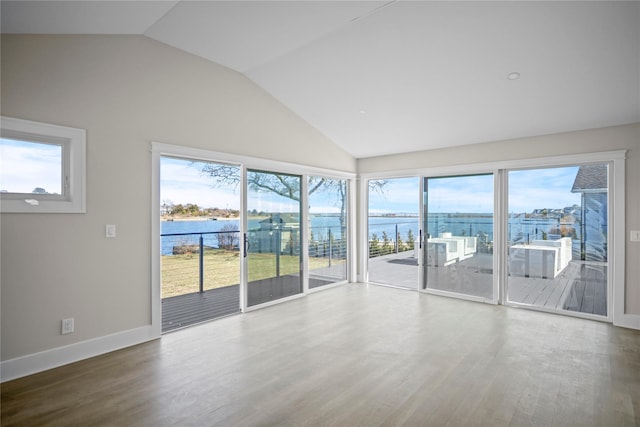unfurnished room with baseboards, vaulted ceiling, wood finished floors, and a water view