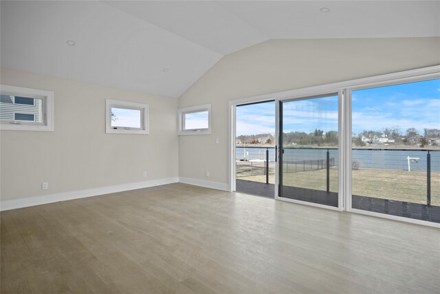 spare room featuring a water view, baseboards, lofted ceiling, and wood finished floors
