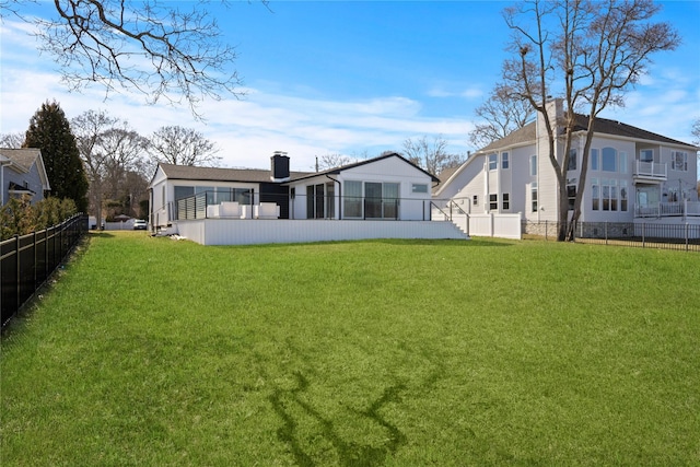 rear view of property featuring a chimney, fence, and a yard