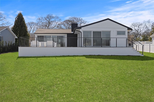 back of house with a lawn, a chimney, and fence