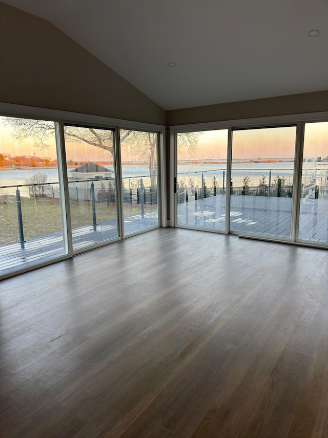 unfurnished room featuring a water view, lofted ceiling, and wood finished floors