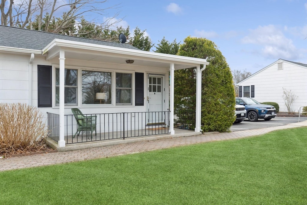 55075 Main Rd Unit 1, Southold, NY 11971 - view of front of home with roof with shingles, a porch, and a front lawn