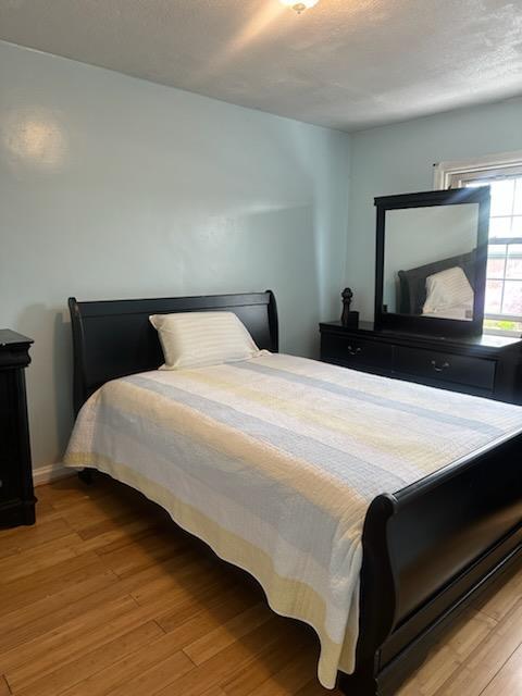 225-23 Murdock Ave, Queens Village, NY 11429 - bedroom featuring baseboards, wood finished floors, and a textured ceiling