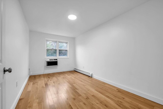 104-65 42nd Ave, Corona, NY 11368 - spare room featuring light wood finished floors, a wall mounted air conditioner, baseboards, and a baseboard radiator