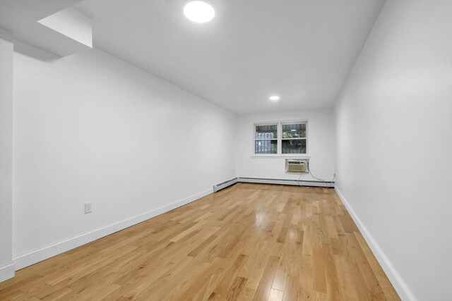 104-65 42nd Ave, Corona, NY 11368 - spare room with light wood-style flooring, an AC wall unit, a baseboard heating unit, and baseboards