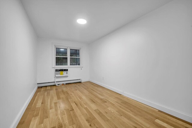 104-65 42nd Ave, Corona, NY 11368 - unfurnished room featuring an AC wall unit, light wood-style flooring, baseboards, and baseboard heating