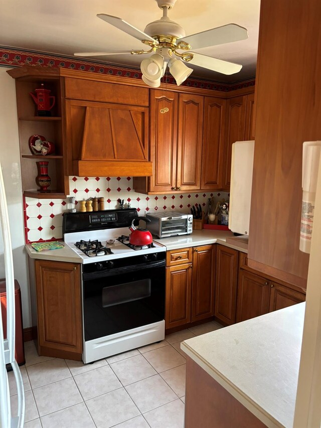 67-66 108th St Unit B64, Forest Hills, NY 11375 - kitchen with range hood, a ceiling fan, brown cabinetry, light countertops, and gas range oven