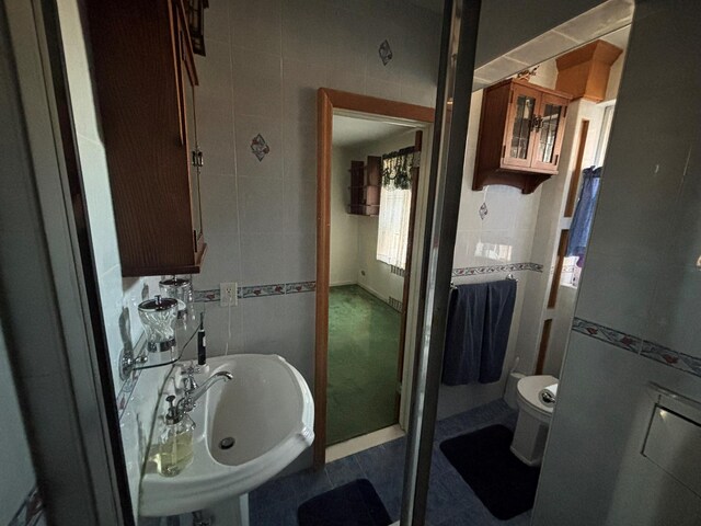 67-66 108th St Unit B64, Forest Hills, NY 11375 - bathroom with tile patterned floors, toilet, tile walls, and a sink