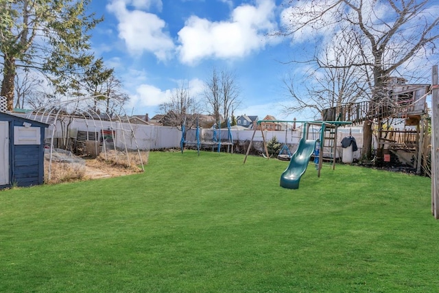 view of yard with a trampoline, a fenced backyard, and a playground