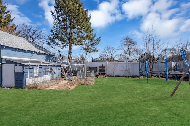 view of yard featuring an outdoor structure, a trampoline, and fence