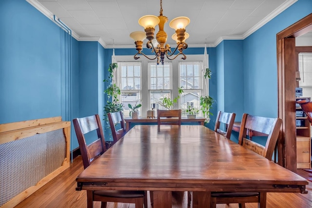 dining area with an inviting chandelier, wood finished floors, and ornamental molding