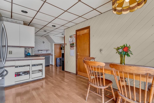 dining area with light wood finished floors and a paneled ceiling