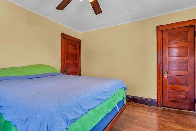 bedroom featuring baseboards, a ceiling fan, wood finished floors, and crown molding