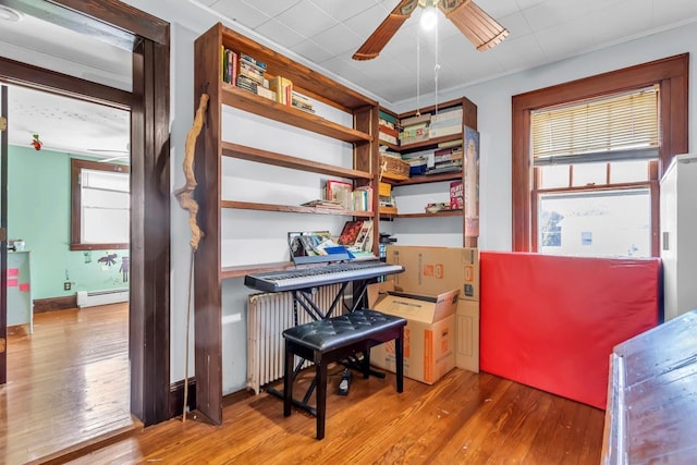 office featuring a baseboard heating unit, wood finished floors, radiator heating unit, and a ceiling fan