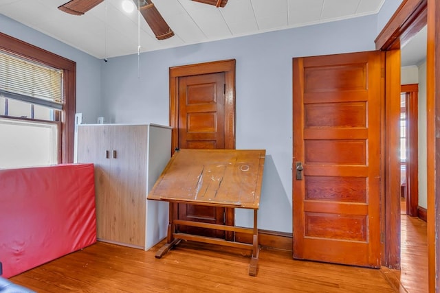 interior space with wood finished floors, a ceiling fan, and crown molding