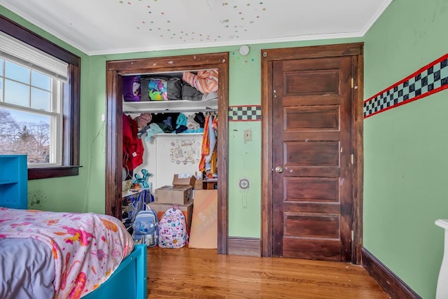 bedroom with wood finished floors, a closet, and ornamental molding