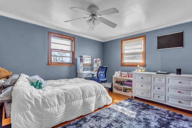 bedroom featuring light wood finished floors, a baseboard heating unit, ceiling fan, and ornamental molding