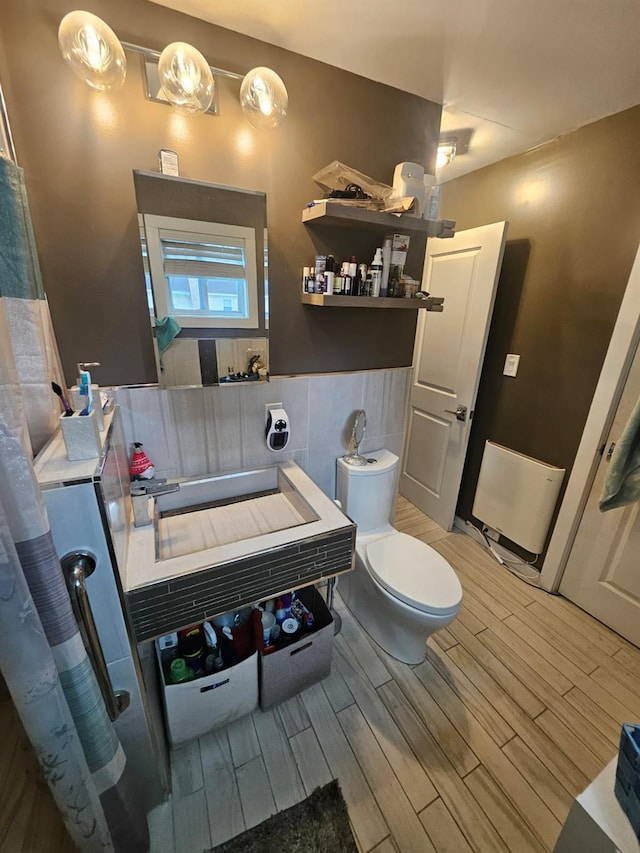 bathroom featuring a wainscoted wall, toilet, tile walls, and wood finish floors