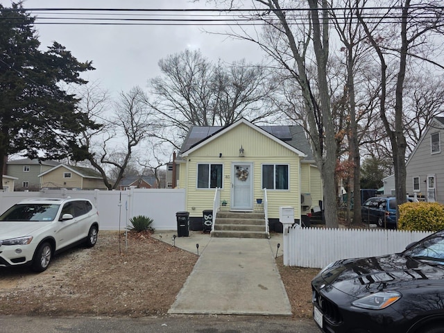 bungalow-style home featuring solar panels, a gate, and fence