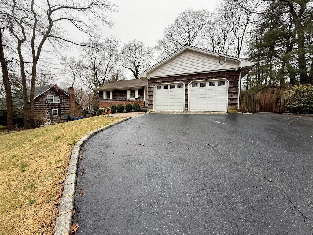 single story home with fence, a front yard, aphalt driveway, and an attached garage