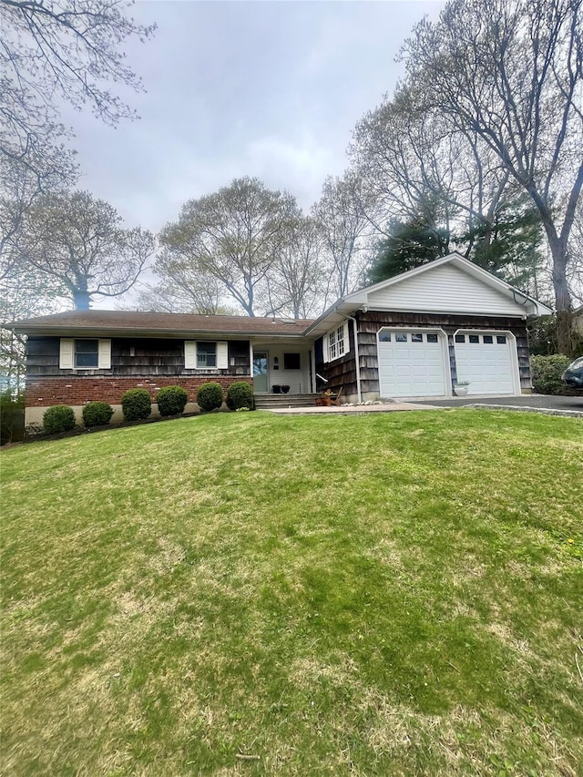 ranch-style home featuring a front yard, an attached garage, covered porch, and aphalt driveway