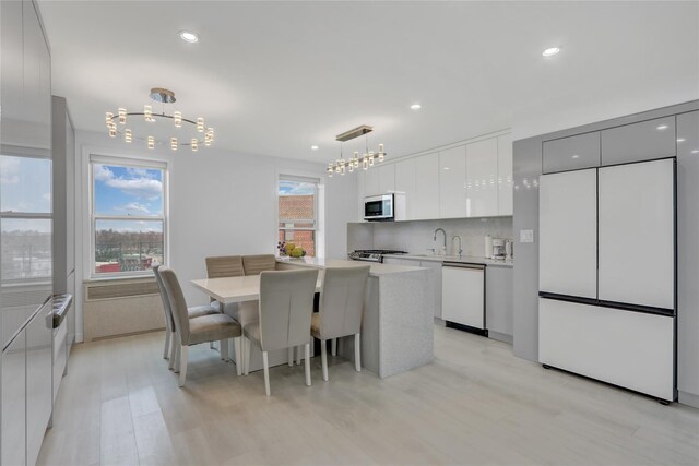 dining space with recessed lighting, a healthy amount of sunlight, light wood-type flooring, and an inviting chandelier