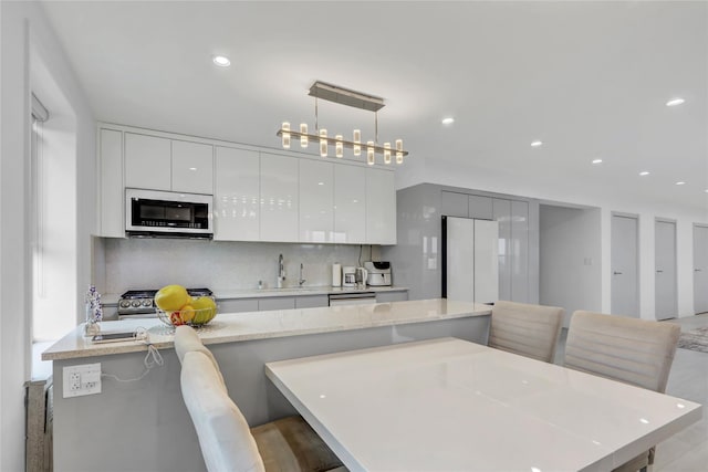 kitchen with stainless steel microwave, a kitchen island, decorative backsplash, freestanding refrigerator, and modern cabinets