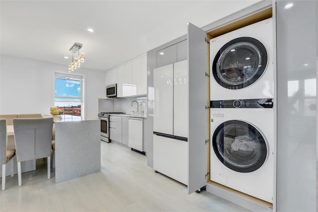 laundry area featuring laundry area, stacked washer / drying machine, and a sink