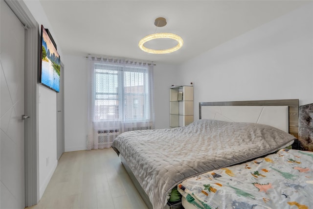 bedroom with a wall unit AC, baseboards, and light wood finished floors