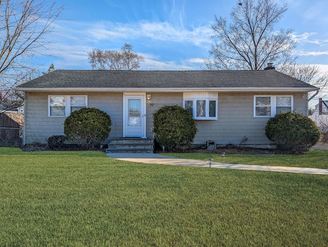 ranch-style house with a shingled roof, a front lawn, fence, and a chimney