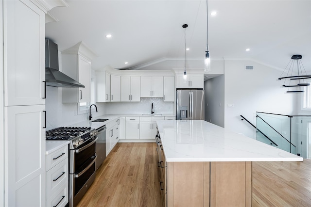 kitchen with vaulted ceiling, a kitchen island, visible vents, wall chimney range hood, and appliances with stainless steel finishes