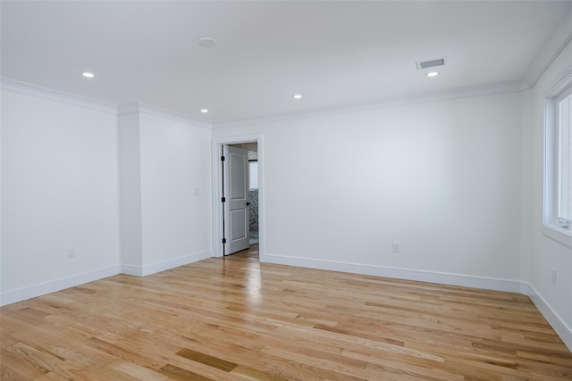 spare room featuring baseboards, visible vents, light wood-type flooring, and ornamental molding