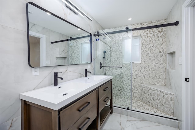 full bath featuring marble finish floor, a sink, double vanity, and a shower stall