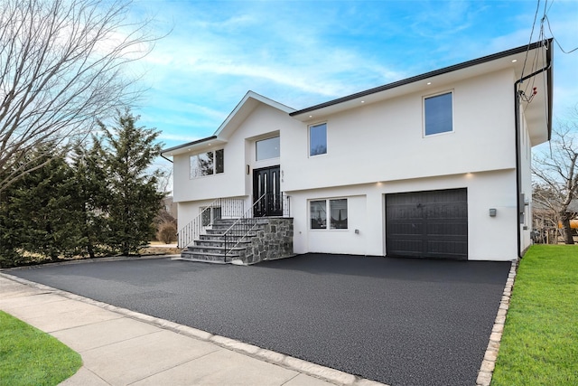 bi-level home with driveway, an attached garage, and stucco siding